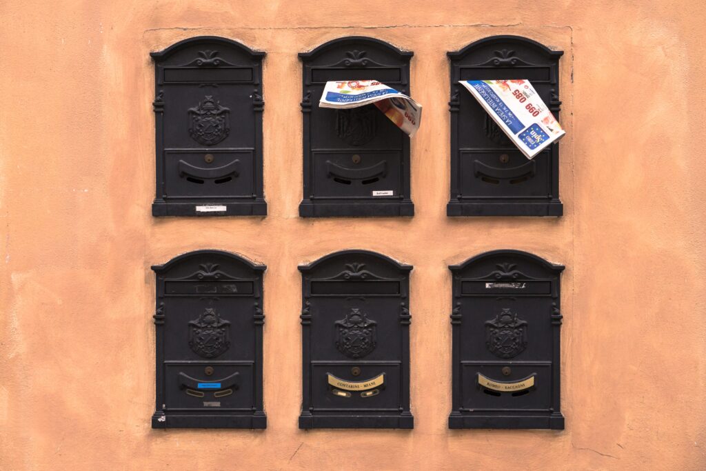 Six black postboxes on a terracotta background