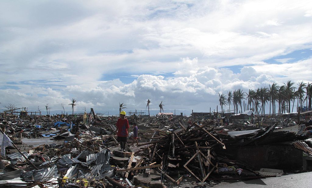 A man stands surrounded by the devastation on a beach