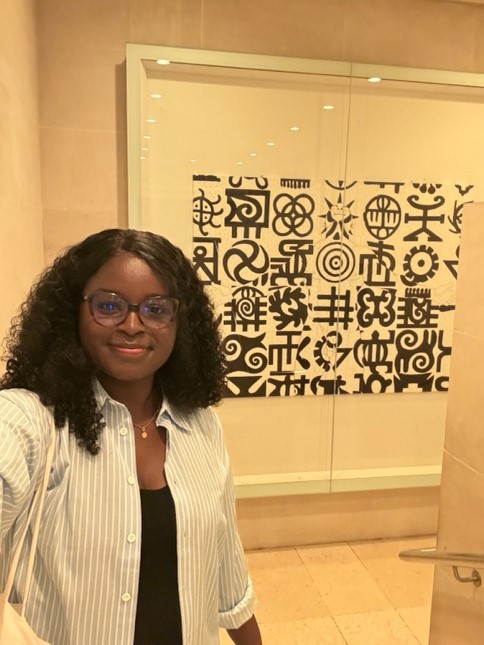 A woman next to Adinkra symbols