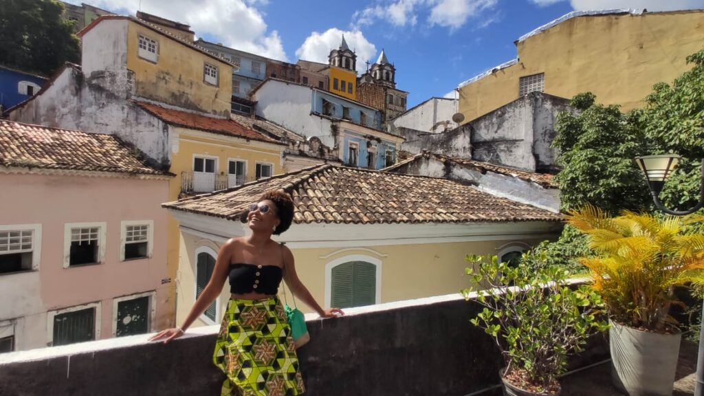 A black woman in yellow dress sitting on a wall