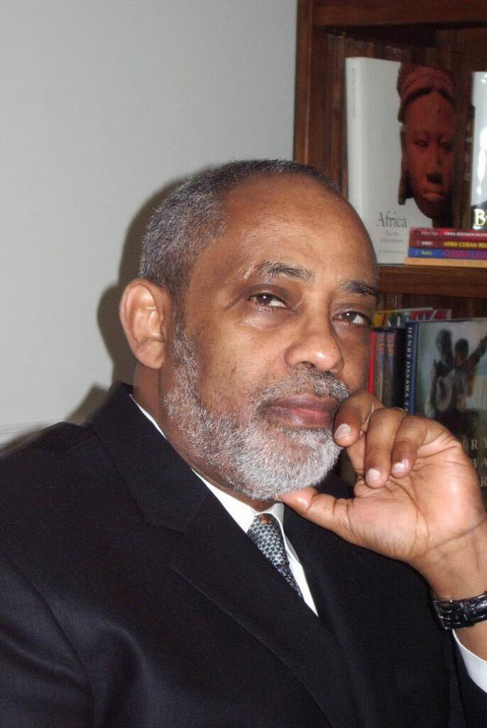A picture of a man next to a book shelf